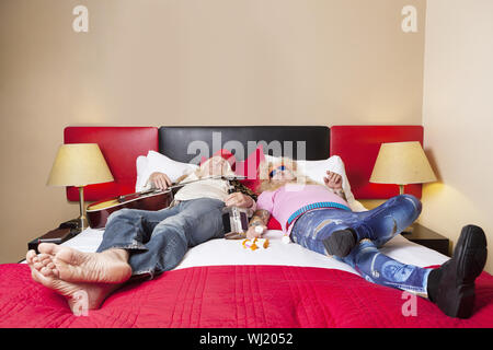 Exhaust male friends sleeping on bed Stock Photo