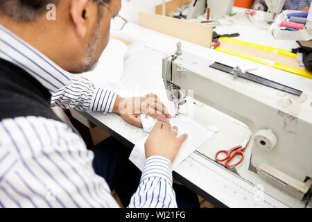 Close-up of man sewing with machine Stock Photo