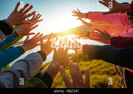 Hands of many friends reaching together for the sun. Friendship or travel concept Stock Photo