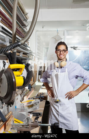 Portrait of a skilled worker standing with hands on hips in workshop Stock Photo