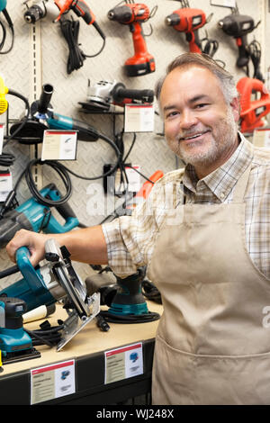 Portrait of a happy salesperson with electric saw in hardware store Stock Photo