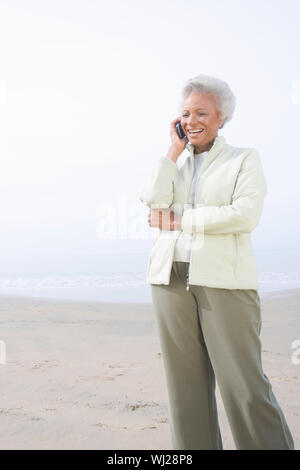 An African American happy senior woman on call at beach Stock Photo