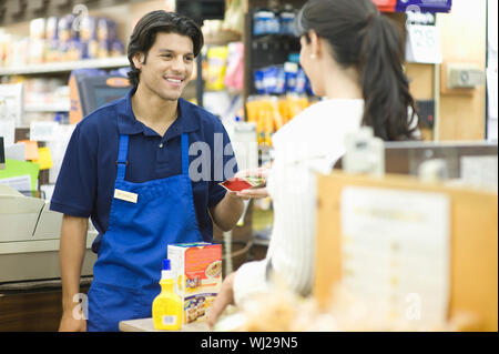 Supermarket employee in blue apron assisting female customer Stock Photo