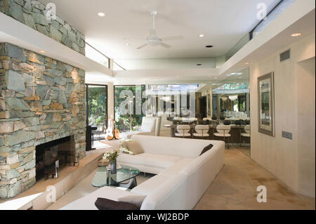 Sunken seating area and stone fireplace with dining area in background at home Stock Photo