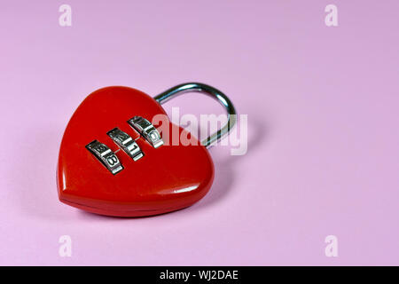 Red metallic lock in the shape of a heart with a security numbers combination mechanism on it , on pink background Stock Photo