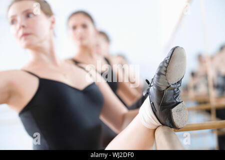 Row of ballerinas practicing at the barre in rehearsal room Stock Photo