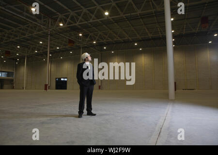 Full length of male architect looking away in empty warehouse Stock Photo