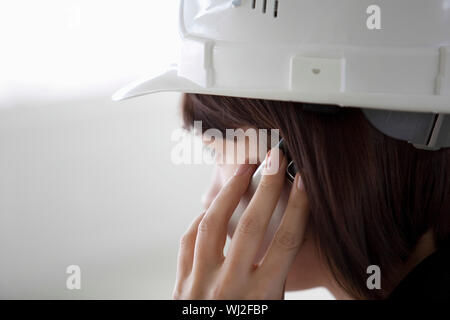 Closeup side view of female architect using cell phone Stock Photo