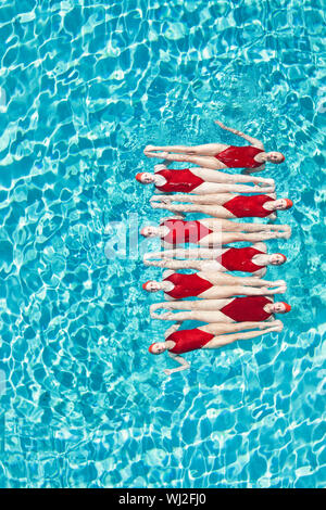 Group of swimmers performing synchronized swimming in pool Stock Photo