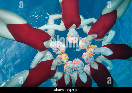 Underwater view of happy synchronized swimmers performing in pool Stock Photo