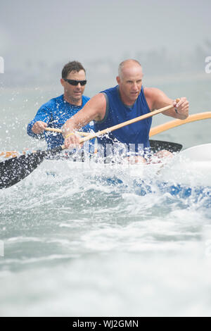 Male rowers paddling outrigger canoe in race Stock Photo
