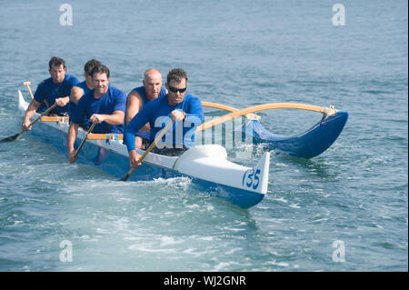 Male rowers paddling outrigger canoe in race Stock Photo