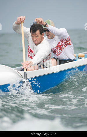 Confident male rowers paddling outrigger canoe in race Stock Photo