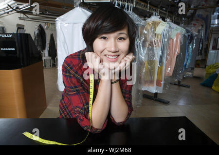 Portrait of happy female owner with hands on chin in laundry Stock Photo