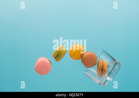 Five coloured macaroons floating from a glass tumbler with a light blue background. Pink, brown, green, yellow and beige Macaroons. Photo detail Stock Photo