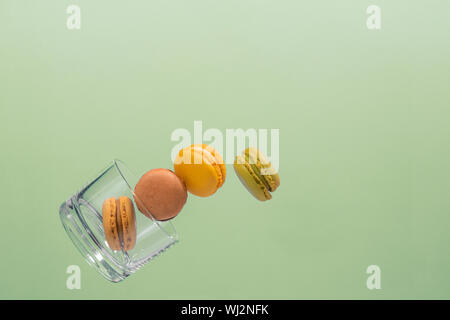 Five coloured macaroons floating from a glass tumbler with a light blue background. Pink, brown, green, yellow and beige Macaroons. Photo detail Stock Photo
