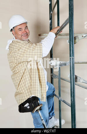 Portrait of a happy worker climbing scaffold Stock Photo