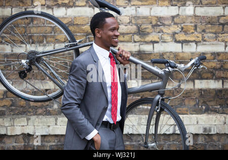 Portrait of African American businessman carrying Bicycle Stock Photo