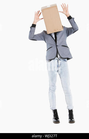 Young boy with box covered over his face and hands raised over gray background Stock Photo