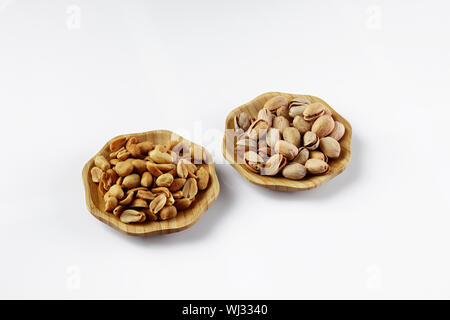 wood plates of salted peanuts and pistachios on white background. snack to beer Stock Photo
