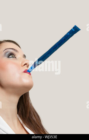 Young woman with party blower against light blue background Stock Photo ...