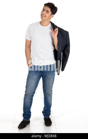 Young man carrying blazer on shoulder with his hands in pocket Stock Photo