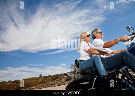 Senior couple riding motorcycle on desert road Stock Photo