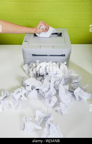 Cropped image of businessman's hand using printer with paper balls on desk Stock Photo