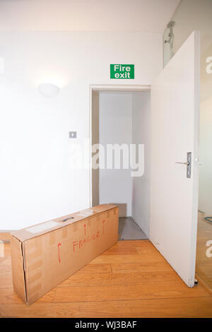 Cardboard box marked 'fragile' by fire exit Stock Photo