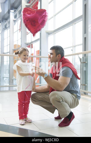 Father gives young daughter heart shaped balloon Stock Photo