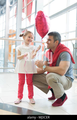 Father gives young daughter heart shaped balloon Stock Photo