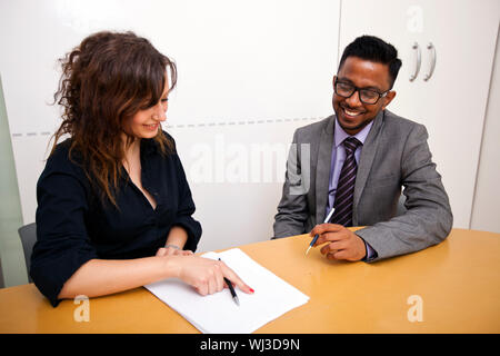 Multi-ethnic work colleagues looking at paperwork on a table Stock Photo