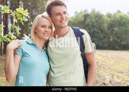 Thoughtful young couple smiling while hiking in forest Stock Photo