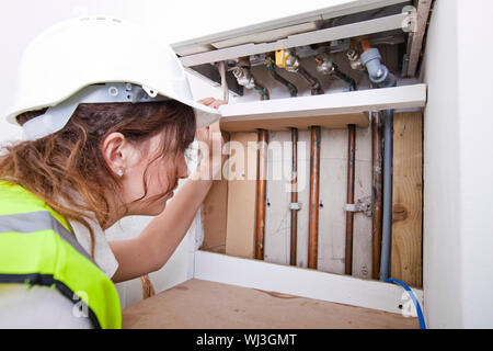 Female plumber examining pipes of central heating boiler Stock Photo
