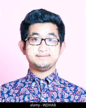 Young Geeky Asian Man in colorful shirt wearing glasses Stock Photo