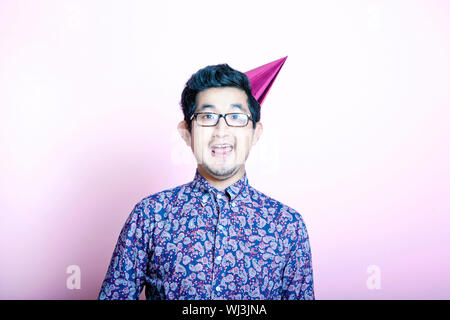Young Geeky Asian Man wearing party hat Stock Photo