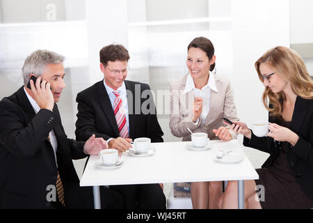 Business executives sitting around a table enjoying a relaxing cup of coffee together during a break Stock Photo