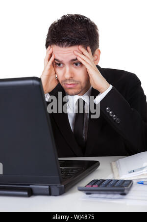 Businessman with a look of hopelessness staring at the screen of his laptop with his head resting in his hands Stock Photo