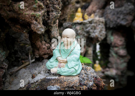 A small, green sitting, content Buddha sits in a rock grotto at the Chinese temple Cheng Hoon Teng in Malacca, Malaysia. Stock Photo