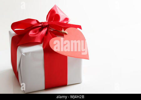 Gift box with red satin ribbon and heart tag Stock Photo