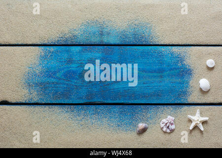 Summer background with yellow sand, starfish and shells on blue wooden backround Stock Photo