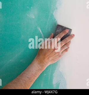 plastering man hand sanding the plaste in drywall seam plasterboard Stock Photo