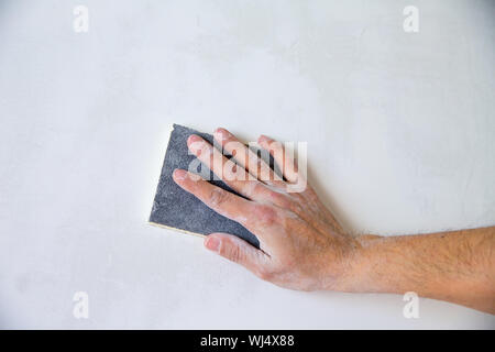 plastering man hand sanding the plaster in white wall Stock Photo