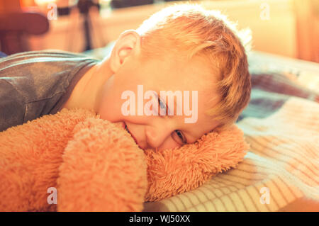 A cute 5 year old boy woke up after a nap. Portrait of a sleepy child at sunset day. The concept of rest. Stock Photo