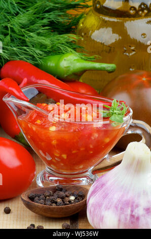 Gravy boat with peppercorn sauce and chili peppers on white background ...