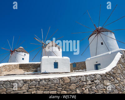 From below ancient windmills and stone walls of Kato Mili against cloudless blue sky in city on Mykonos Island in Greece Stock Photo