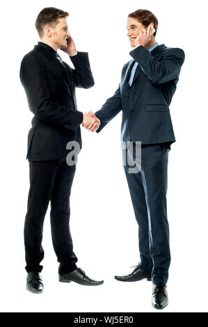 Colleagues shake hands during phone calls Stock Photo