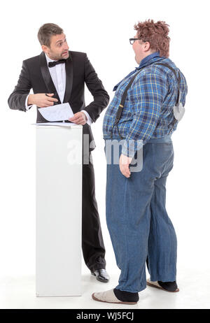 Elegant man in a tuxedo and bow tie standing arguing with an overweight country yokel Stock Photo