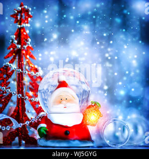 Blue Christmas background with cute snow globe Santa Claus border over blur bokeh lights, magic of Christmas eve and winter holidays, xmas greeting ca Stock Photo