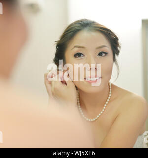 Asian bride wearing earrings on her wedding day. Stock Photo